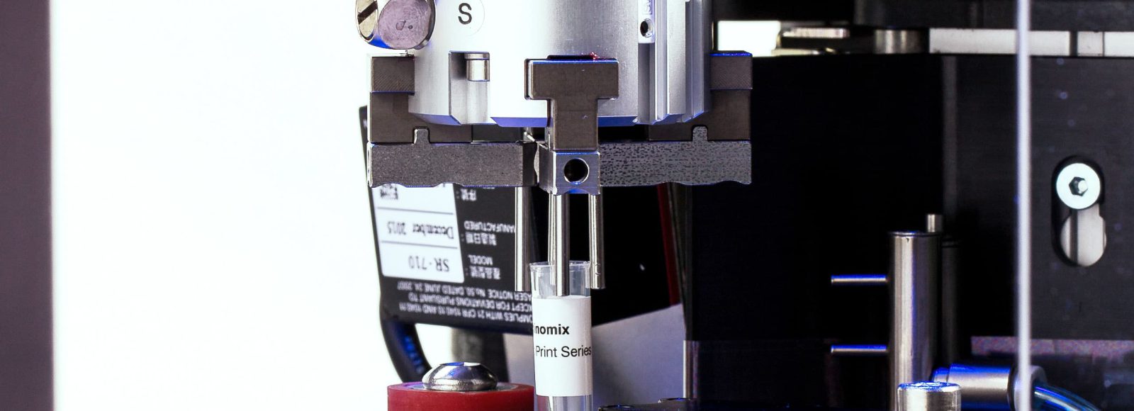 A Miconic tube being held by the gripper finger to be labeled by a Scinomix labeler