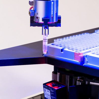 A close-up of the gripper finger holding a labeled tube to be scanned